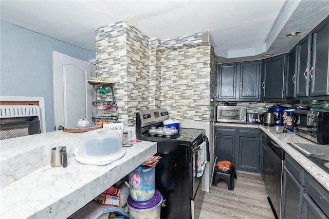 kitchen featuring light wood-type flooring, backsplash, light stone counters, and stainless steel appliances