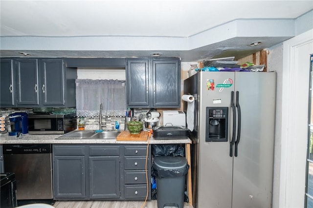 kitchen with gray cabinets, stainless steel appliances, backsplash, light hardwood / wood-style flooring, and sink