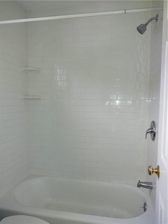 bathroom with toilet and tiled shower / bath combo