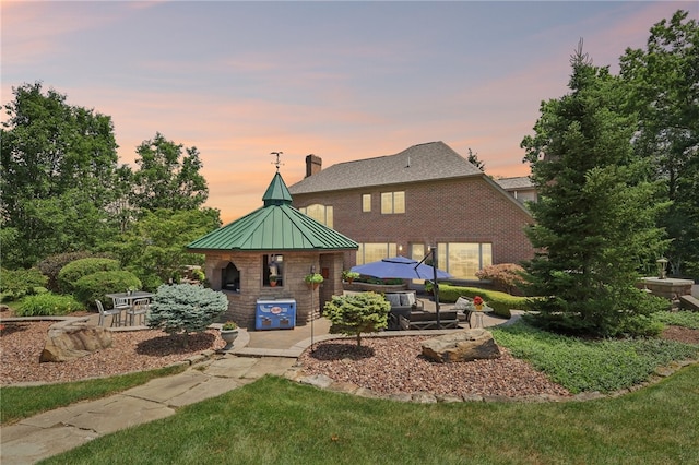 back house at dusk featuring a patio area