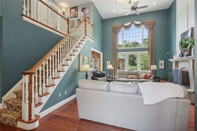 living room featuring dark wood-type flooring, a high ceiling, and ceiling fan