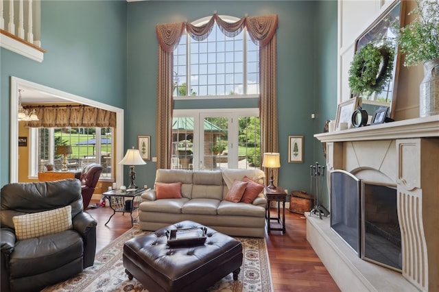 living room with a high ceiling, a fireplace, a wealth of natural light, and wood-type flooring