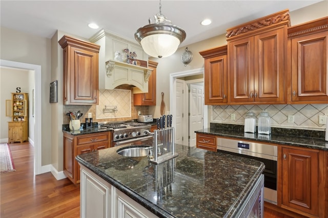 kitchen featuring hanging light fixtures, dark hardwood / wood-style flooring, dark stone counters, tasteful backsplash, and stainless steel oven