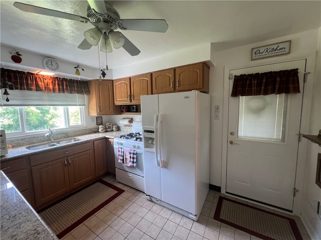 kitchen with ceiling fan, white refrigerator with ice dispenser, gas stove, light tile floors, and sink