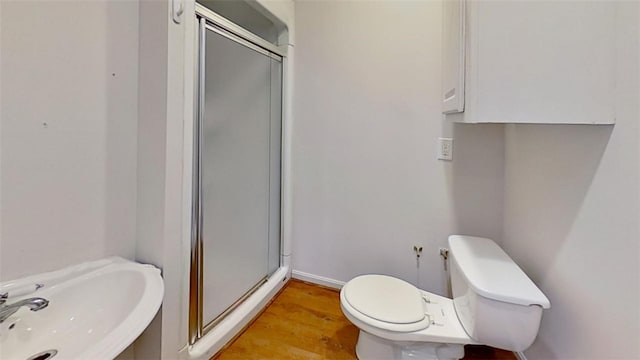 bathroom with hardwood / wood-style floors, toilet, a shower with door, and sink