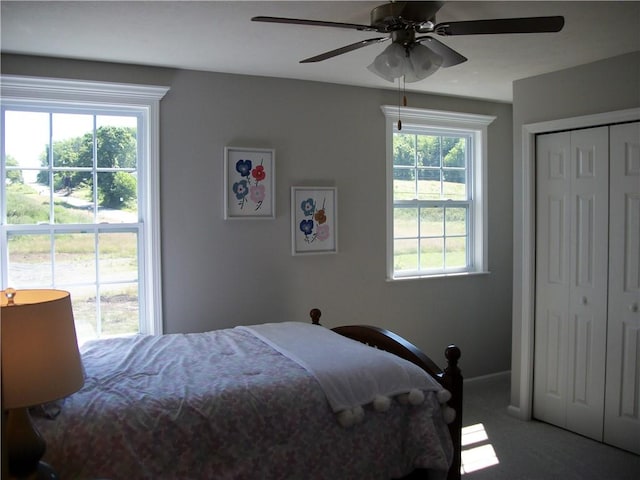 carpeted bedroom with multiple windows, a closet, and ceiling fan