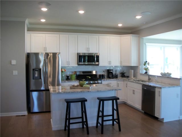 kitchen with white cabinetry, sink, stainless steel appliances, and a center island