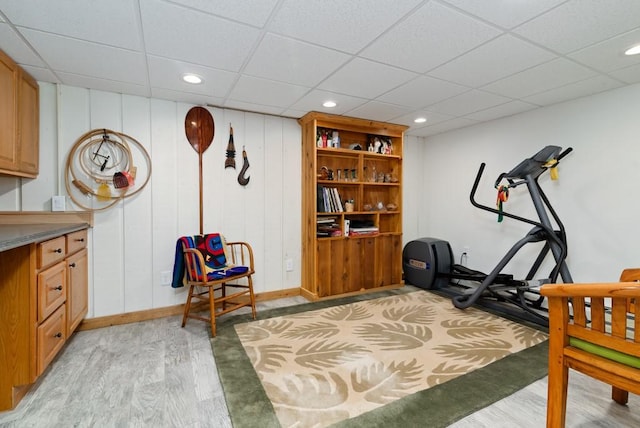 workout room with a paneled ceiling and light hardwood / wood-style floors