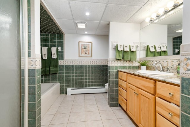 bathroom featuring tile walls, a baseboard heating unit, vanity, tile patterned floors, and toilet