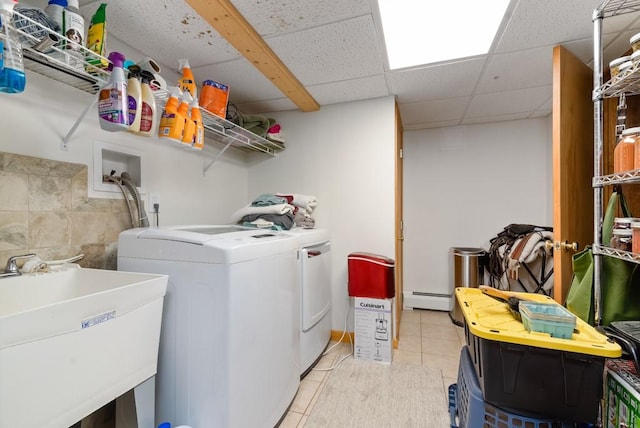 washroom featuring a baseboard radiator, sink, light tile patterned flooring, and washer and clothes dryer