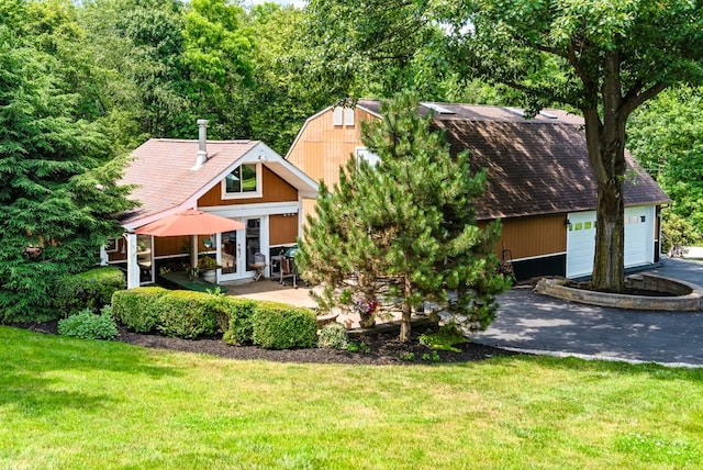 exterior space with a garage, an outdoor structure, and a front lawn