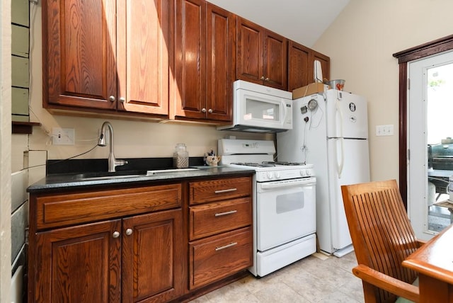 kitchen with white appliances, lofted ceiling, and sink