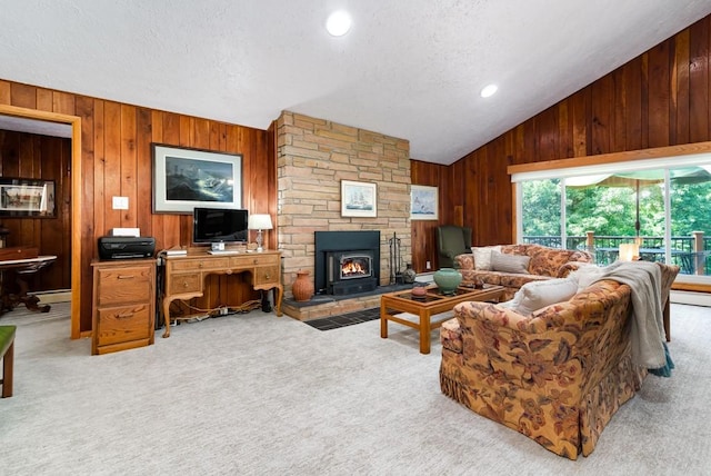 living room featuring vaulted ceiling, a fireplace, wooden walls, a baseboard radiator, and light colored carpet