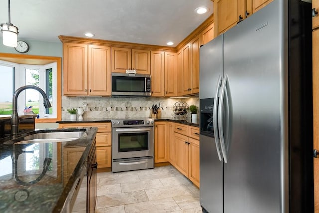 kitchen with sink, decorative light fixtures, dark stone counters, and appliances with stainless steel finishes