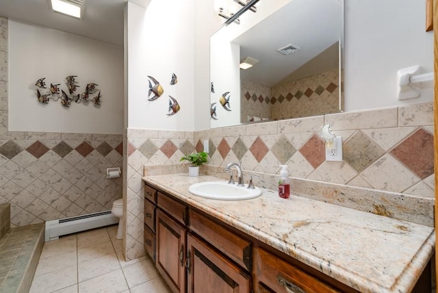 bathroom featuring tile walls, vanity, a baseboard heating unit, toilet, and tile patterned floors