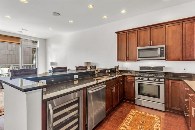 kitchen with wine cooler, kitchen peninsula, stainless steel appliances, hardwood / wood-style floors, and sink