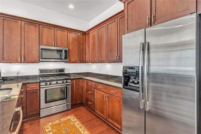 kitchen featuring appliances with stainless steel finishes, hardwood / wood-style floors, and dark stone counters