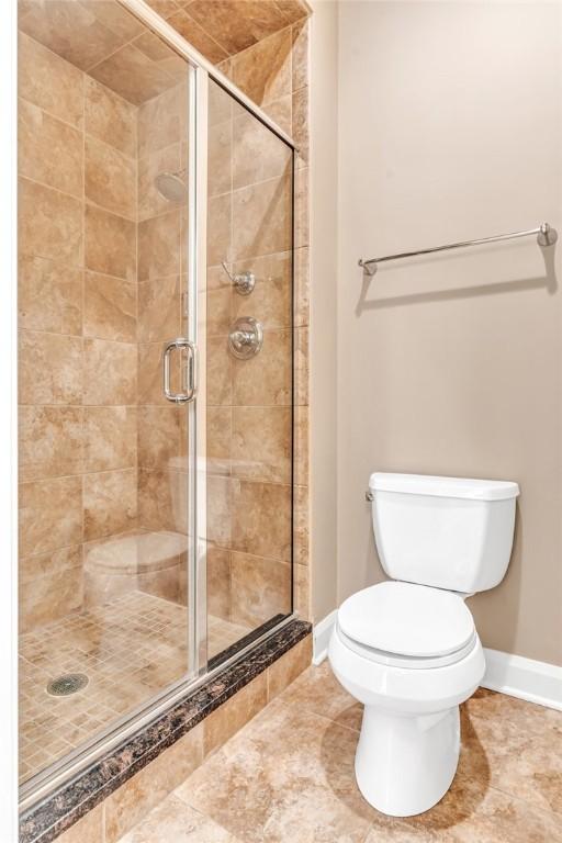 bathroom with an enclosed shower, tile patterned flooring, and toilet