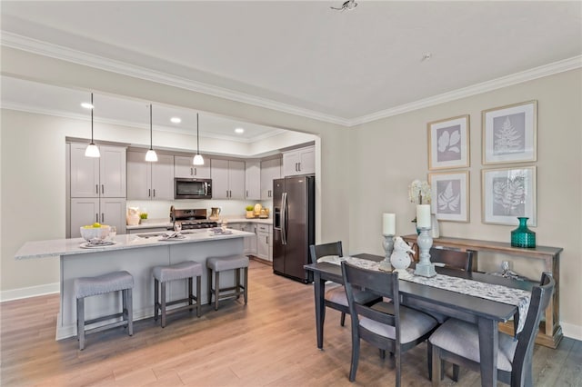 dining space with light wood-type flooring and ornamental molding