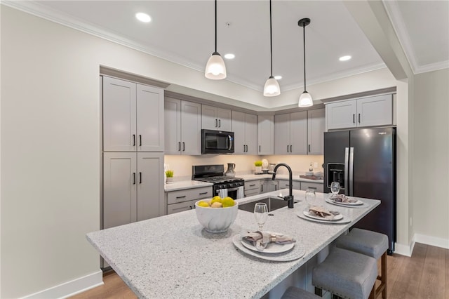 kitchen with pendant lighting, stainless steel appliances, hardwood / wood-style floors, and an island with sink