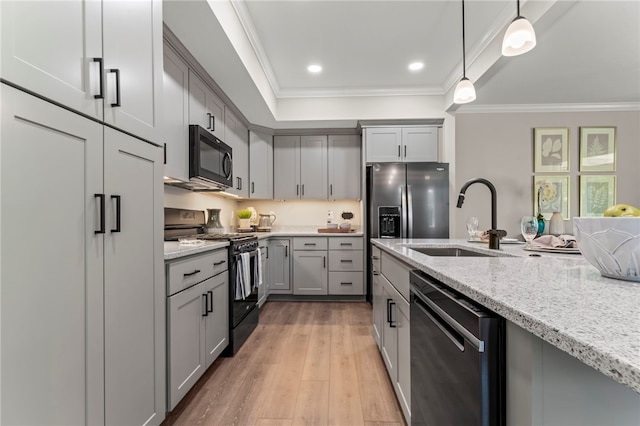 kitchen with stainless steel appliances, hanging light fixtures, ornamental molding, sink, and light hardwood / wood-style floors