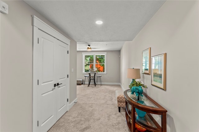 hallway featuring light carpet and a textured ceiling