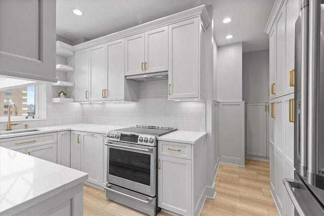 kitchen with stainless steel appliances, white cabinetry, sink, and light stone countertops