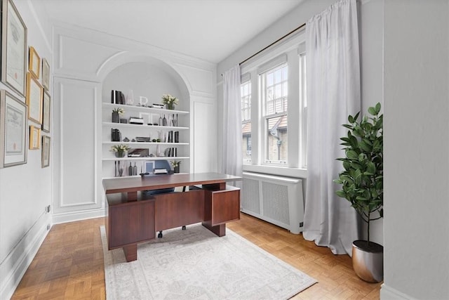 office area with parquet flooring, built in features, and radiator