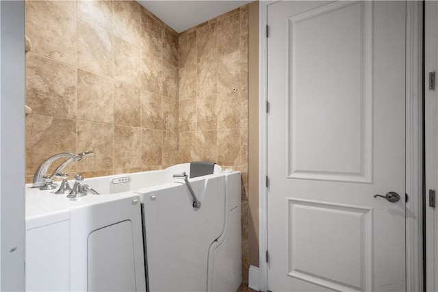 bathroom with a bath and tile walls