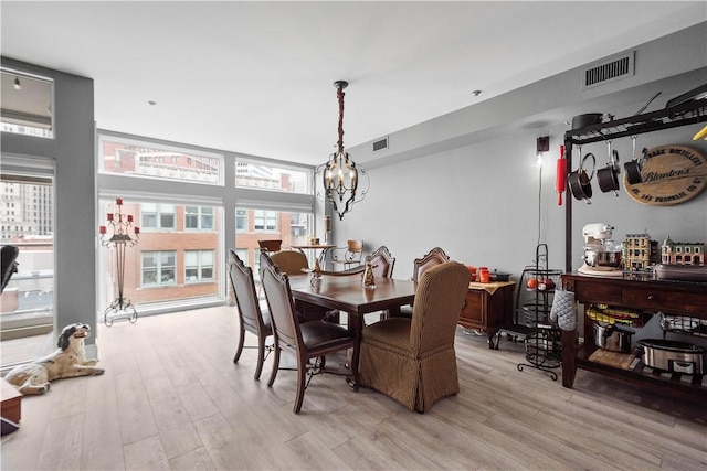 dining room featuring a chandelier, light wood finished floors, and visible vents