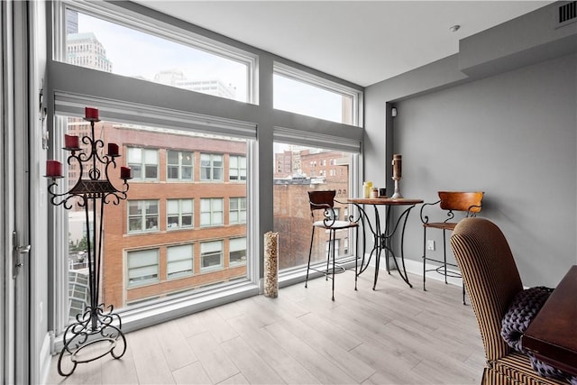 doorway featuring light wood-style flooring, expansive windows, visible vents, baseboards, and a view of city