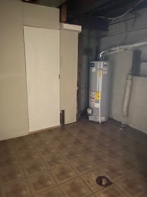 basement featuring dark tile patterned flooring and gas water heater