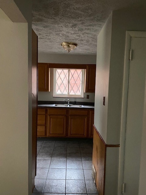 kitchen featuring sink, light tile patterned flooring, and a textured ceiling