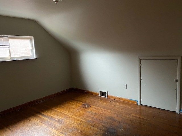 additional living space with wood-type flooring and vaulted ceiling