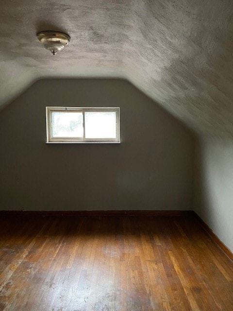 bonus room with vaulted ceiling, a textured ceiling, and hardwood / wood-style floors