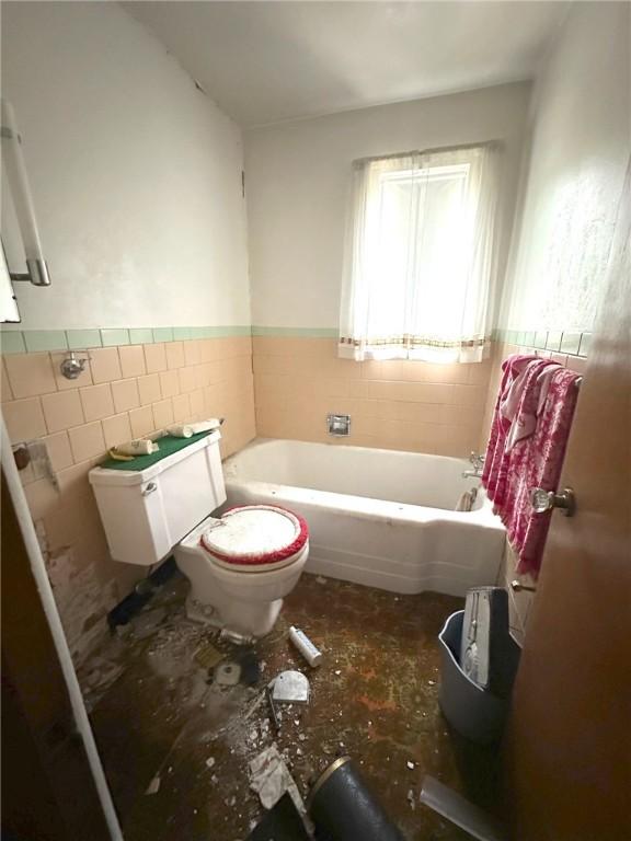 bathroom featuring tile walls, a bath, and toilet