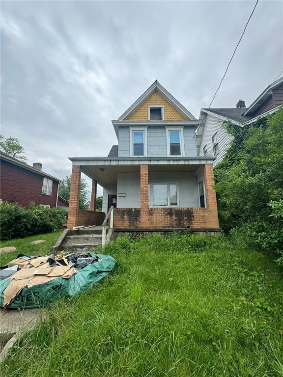 rear view of property with a porch and a lawn