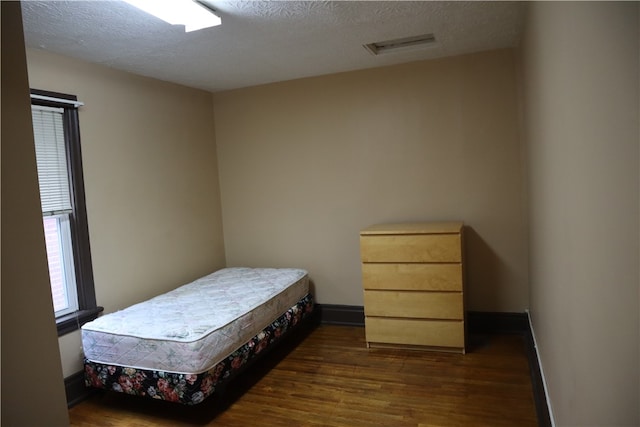 bedroom with dark wood-type flooring and a textured ceiling