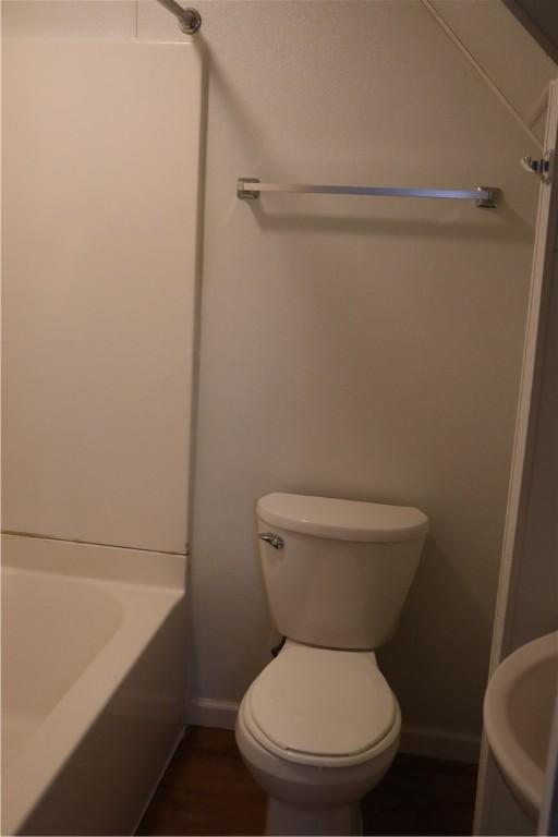 bathroom with shower / washtub combination, wood-type flooring, and toilet