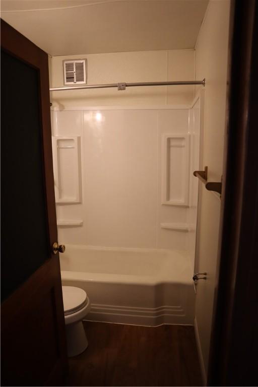 bathroom featuring shower / bathing tub combination, hardwood / wood-style floors, and toilet