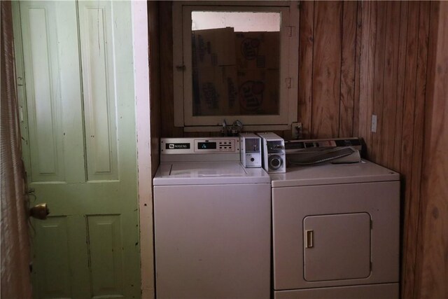 laundry area with washing machine and clothes dryer and wood walls