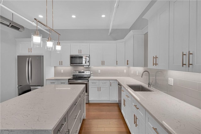 kitchen with tasteful backsplash, stainless steel appliances, sink, white cabinetry, and hanging light fixtures