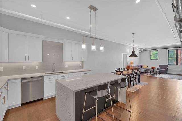 kitchen with a kitchen breakfast bar, stainless steel dishwasher, sink, white cabinets, and a kitchen island