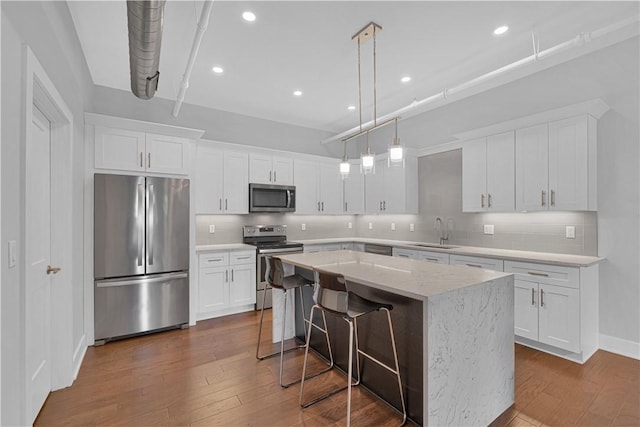 kitchen featuring stainless steel appliances, a kitchen island, white cabinetry, and sink