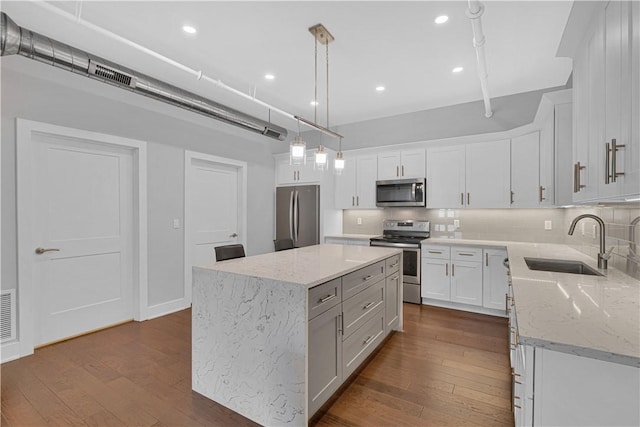 kitchen featuring white cabinets, stainless steel appliances, a kitchen island, and sink