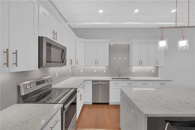 kitchen featuring appliances with stainless steel finishes, backsplash, sink, pendant lighting, and white cabinetry