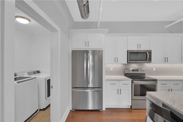 kitchen featuring washer and dryer, decorative backsplash, white cabinetry, and stainless steel appliances