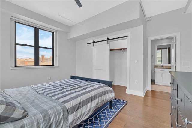 bedroom featuring a barn door, ceiling fan, a closet, and multiple windows