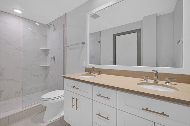 bathroom with tiled shower, vanity, and toilet