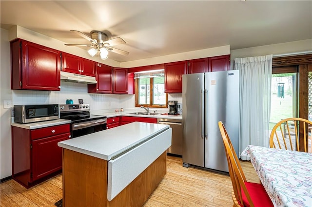 kitchen with ceiling fan, light hardwood / wood-style floors, a kitchen island, sink, and appliances with stainless steel finishes